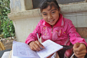 Niña estudiando en su casa en guatemala gracias al programa NPH UnaFamilia Unida de reintegración familiar