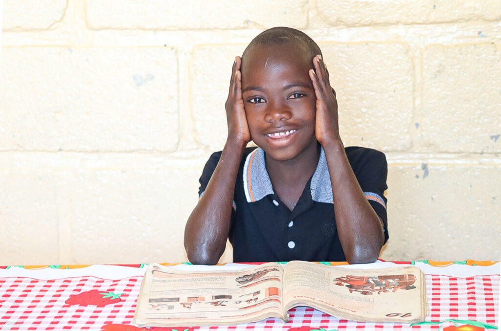 Niño de 7 años sonriendo en un centro educativo de NPH Haití, en un entorno seguro y cuidado.