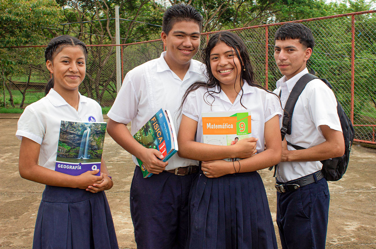 Niñas y niños uniformados entrando a la escuela de NPH en Nicaragua, con mochilas y sonrisas, al inicio de la jornada escolar.
