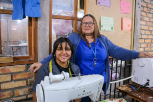 Adolescente de NPH Honduras con docente en taller vocacional de costura